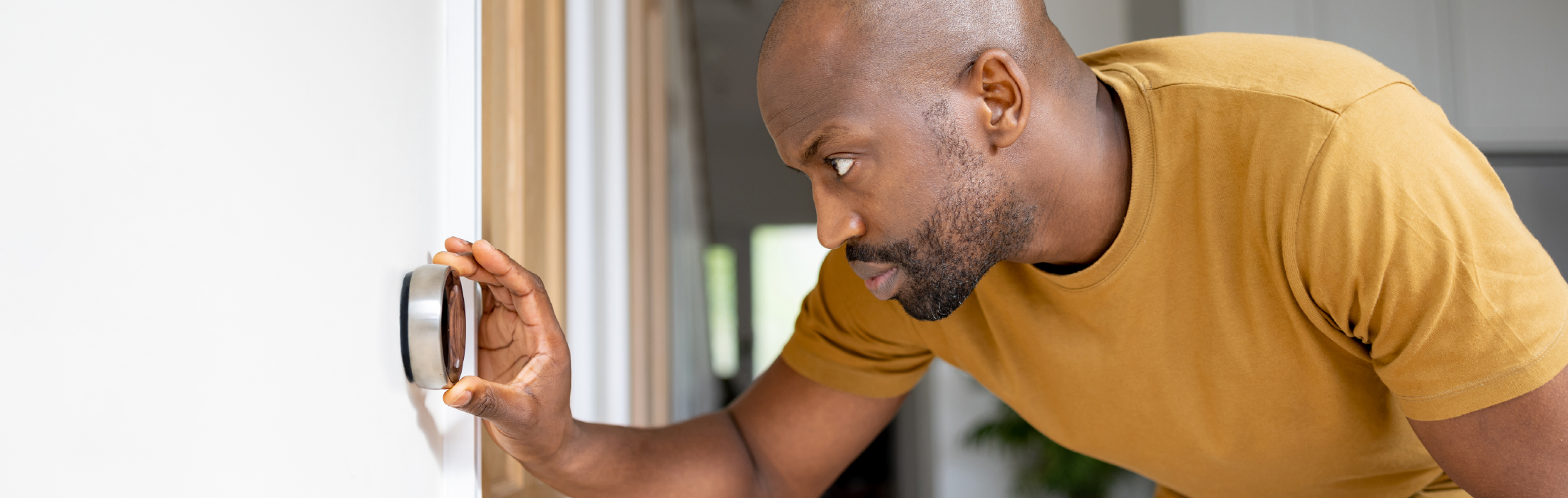 Attractive African American man adjusting programmable thermostat