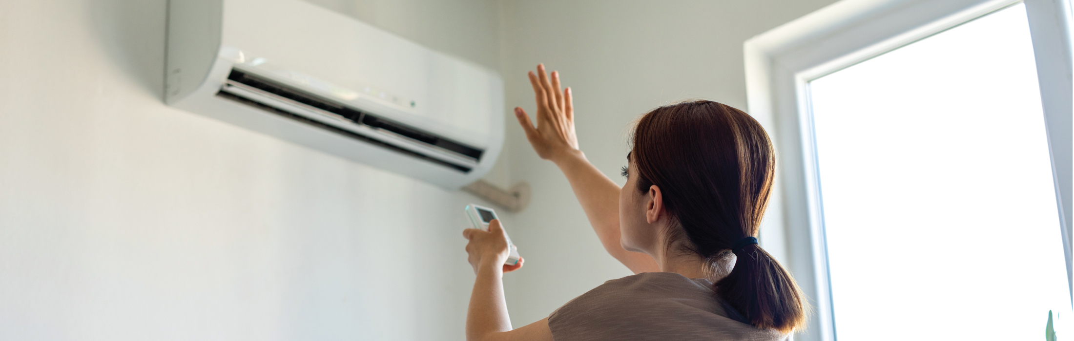 woman testing HVAC unit because it's blowing hot air