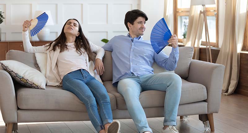 couple fanning themselves in their home