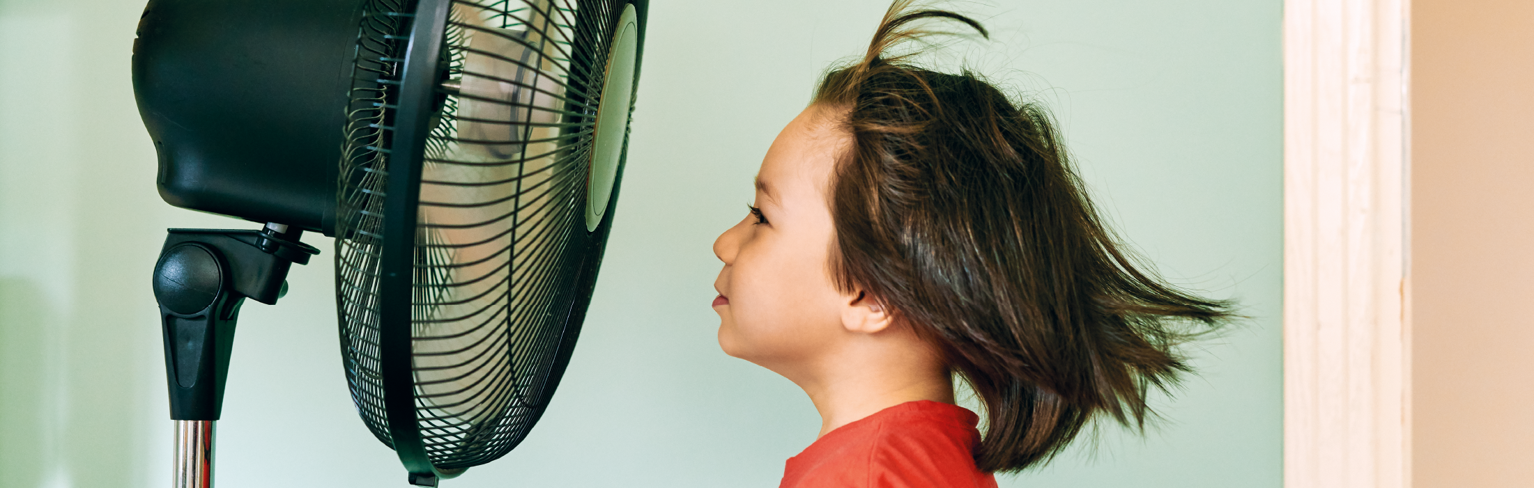 Cute child is front of electric fan on hot summer day stock photo