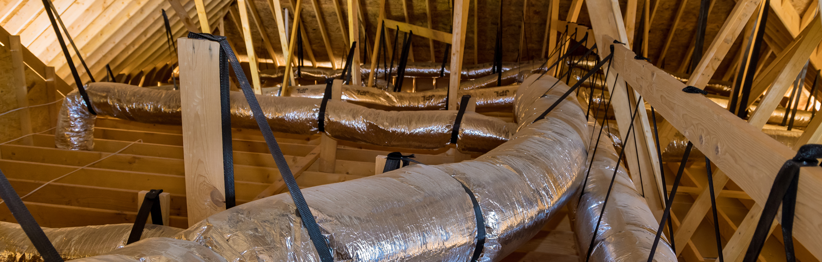 In newly built home under construction ventilation pipes are silver insulation material on ceiling of attic