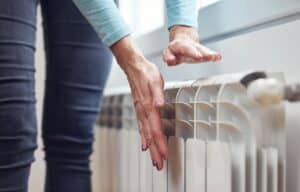%Imagetitle% | Chancey &Amp; Reynolds A person in Alcoa, TN holds their hands above a white radiator, warming them near a window. emergency HVAC service near me