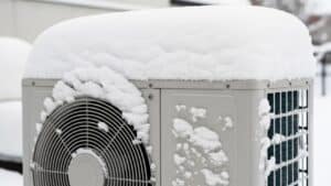 An outdoor air conditioning unit in Alcoa, TN, is covered in a thick layer of snow during winter. Heat pump vs gas furnace Heat pump repair
